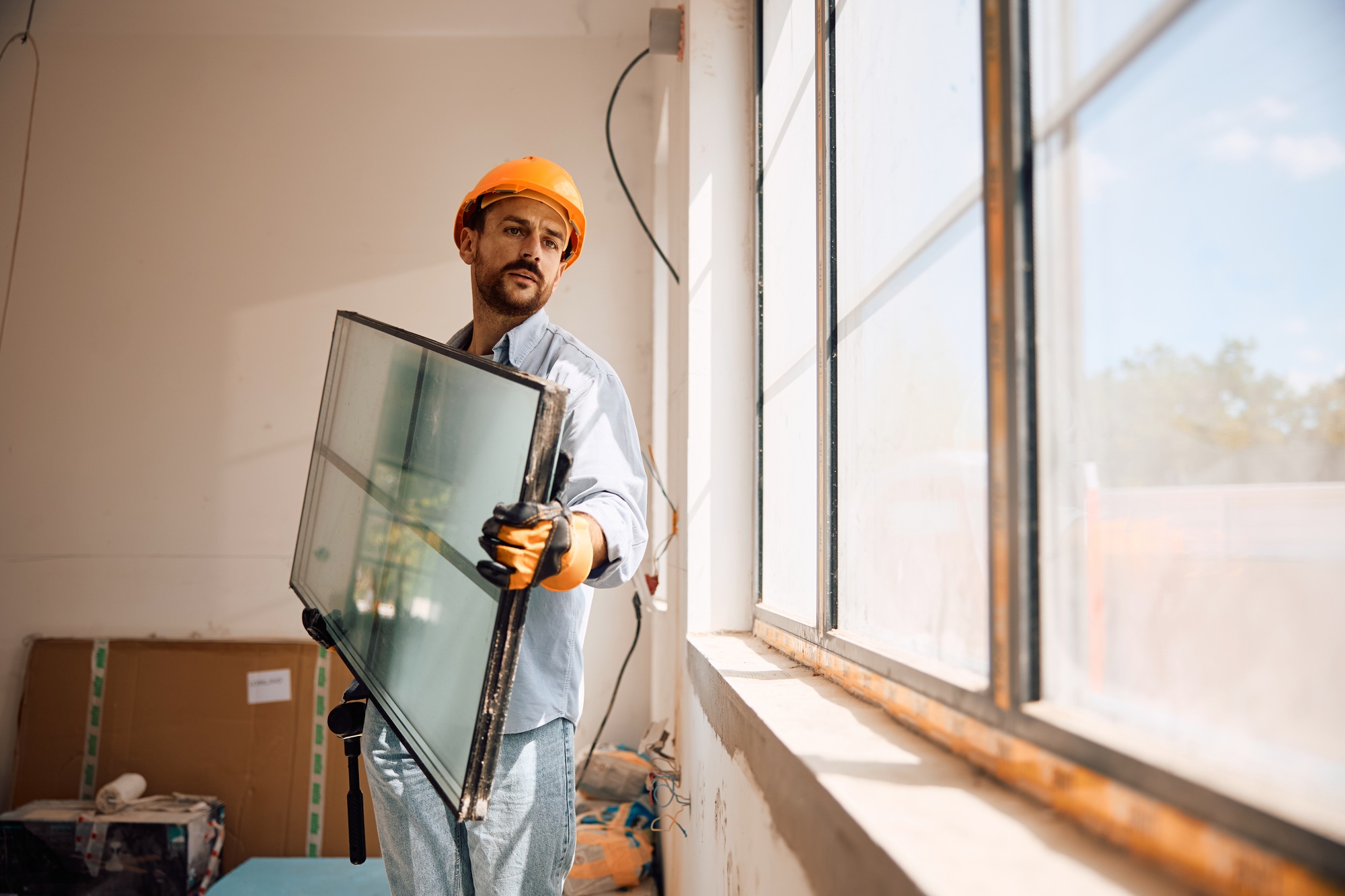 Male worker installing new windows during home renovation process.